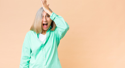 middle age cool woman raising palm to forehead thinking oops, after making a stupid mistake or...