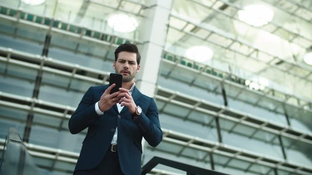 Closeup businessman picking up phone. Man standing in luxury suit near stadium