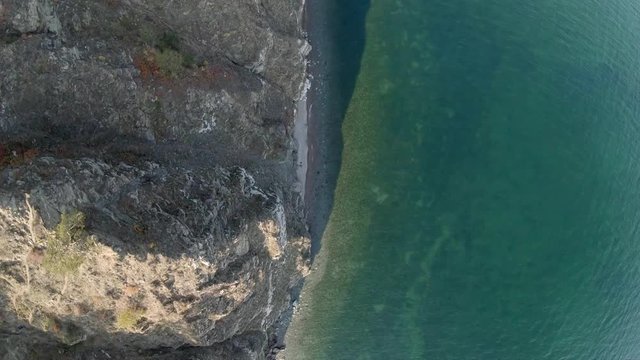 Drone flying above the coastline of sea. Aerial view of Lake Baikal shoreline top down