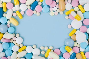 Assorted colorful medicine pills on blue background with copy space