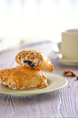 Fresh and rouge rolls with nuts, raisins and meringues on a wooden table and a cup with aromatic coffee