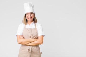 middle age baker woman looking like a happy, proud and satisfied achiever smiling with arms crossed...