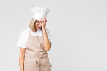 middle age baker woman laughing and slapping forehead like saying d’oh! I forgot or that was a...