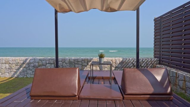 Couples of beachside relaxing chairs with canopy on the resort with oceanfront with an amazing view of ocean waves.