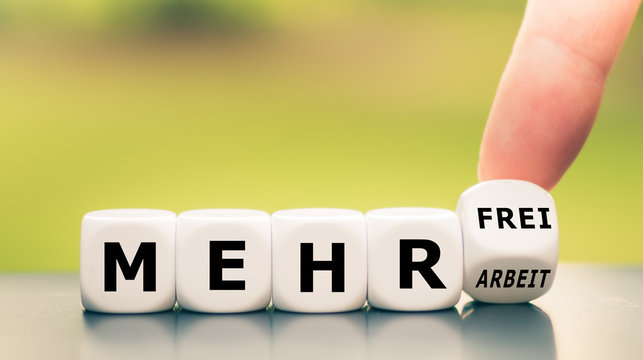 Hand turns dice and changes the German expression "mehr Arbeit" ("more work") to "mehr frei" ("more spare time").