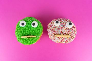 Two delicious cakes with funny faces, pink background and copy space