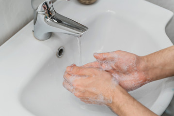 wash your hands with soap under the foam tap in the bathroom, hygiene, clean hands. the man washes...