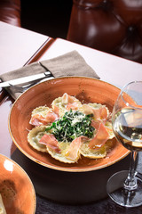 fresh cooked ravioli pasta with prosciutto, walnuts and parmesan cheese on wooden table