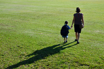 Rear view of mother and daughter walking together to school