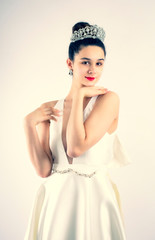Female young model in studio wearing white wedding dress and diadem. High key studio shot. dark hair fashion image