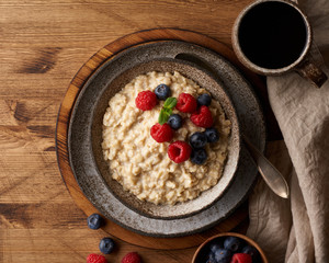 Oatmeal rustic porridge with blueberry, raspberries in ceramic vintage bowl, dash diet with berries