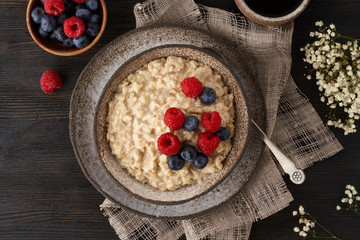 Oatmeal rustic porridge with blueberry, raspberries in ceramic vintage bowl, dash diet with berries