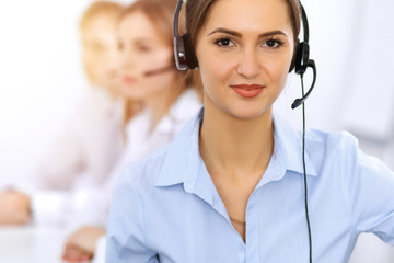 Call center. Focus on beautiful business woman using headset in sunny office