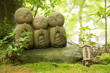 Photograph of three small statues of Buddha praying on a log