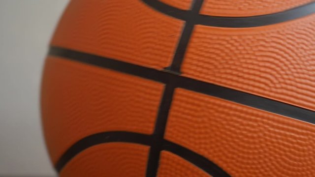 Slow motion orange basketball ball rolls side to side close up. Fragment, black stripes, texture. Sport geometric background