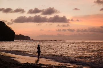 A woman walks into the sea during the sunset in Bali