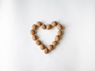 In shell walnuts in a heart shape on a white background. Top view