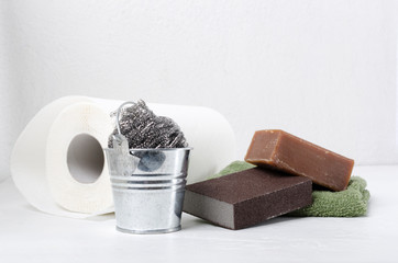 Concept of green cleaning products.Paper, sponges, soap, scrubber, metal bucket on the white table