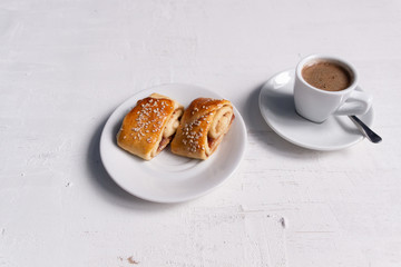 cup of coffee and saucer with dessert on white concrete background