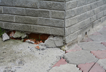 Poorly constructed foundation of the house. Ashlar facade bricks are broken damaging the foundation.
