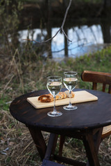 Spring picnic on nature – white wine in glasses and grill bread on wooden round table
