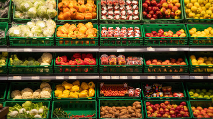 Various vegetables tomatoes, cucumbers, cabbage are sold at vegetable shop. Vegetables lie on shelf in grocery store.