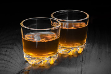 two glasses of cognac on a black tree