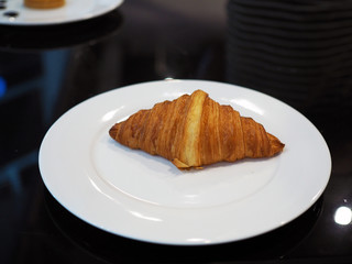 A crispy baked croissant isolated on white plate. Breakfast concept.