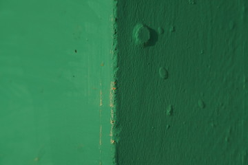Old corner of a painted green wall with blemishes