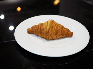 A crispy baked croissant isolated on white plate. Breakfast concept.