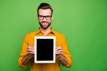 Portrait of nice attractive cheerful content guy in formal shirt holding in hands showing digital tablet new product isolated on bright vivid shine vibrant green color background