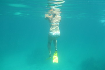 A woman resting at the surface while drifting and snorkeling seen from under water