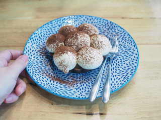 Homemade banoffee pie topped with cocoa powder, made from fresh slice ripe banana, cream, toffee and crumbled biscuits.