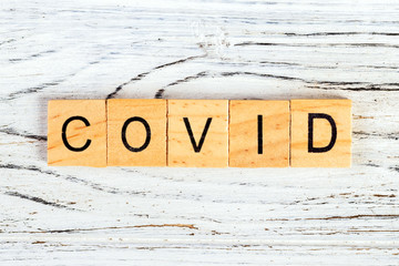 Inscription COVID on wooden background. Covid word written on wood block. text on wooden table for...