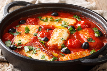 Cyprus food baked Halloumi with tomatoes, peppers, olives in a spicy sauce close-up in a pan....