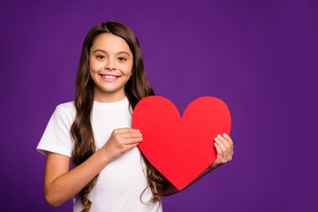 Close-up portrait of her she nice attractive lovely lovable cheerful wavy-haired girl holding in hand big large heart symbol isolated on bright vivid shine vibrant purple violet lilac color background