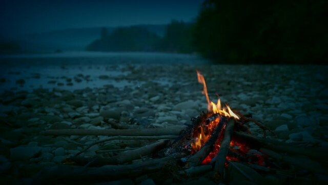 Close-up Campfire Near Mountain River On Rocky Shore. Hiking in Mountain Forest Park. Active Tourism Traveling