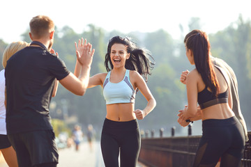 Girl runner runs fun with a group of friends in a park