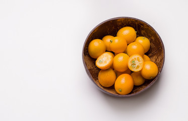 tropical citrus fruit kumquat in a coconut bowl on a white background. copy space