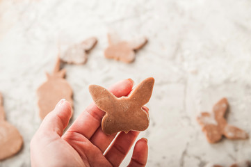 The process of making ginger Easter gingerbread cookies closeup. Gingerbread tenderloin in the shape of bunnies and eggs. Hands prepare dough, cookies and copy space.