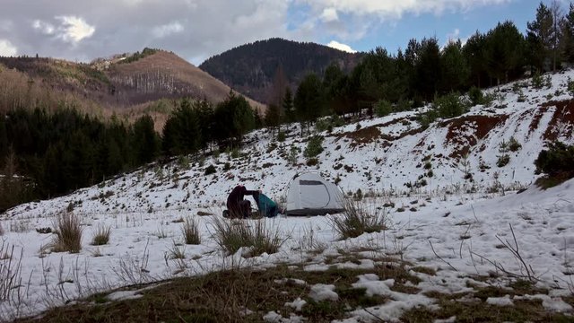 Hiker pitching tent in winter in the mountains.