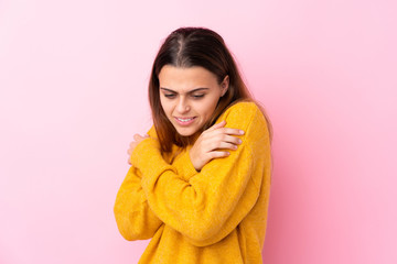 Teenager girl with yellow sweater over isolated pink background freezing
