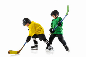 Little hockey players with the sticks on ice court and white studio background. Sportsboys wearing equipment and helmet practicing. Concept of sport, healthy lifestyle, motion, movement, action.