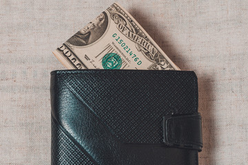 20 dollars sticking out of a wallet of dark leather on a gray background.