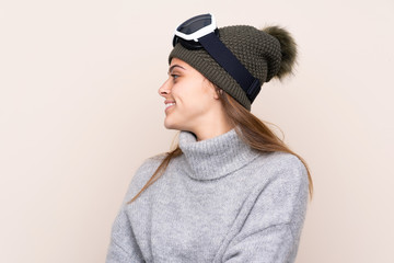 Teenager skier girl with snowboarding glasses over isolated background looking side