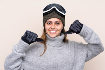 Teenager skier girl with snowboarding glasses over isolated background proud and self-satisfied