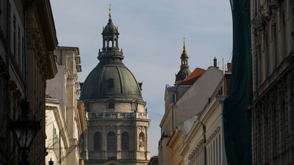 Fototapeta na wymiar Detailed view of neoclassical 18th century dome or cupola of a catholic church basilica at the end of the street framed with other buildings on the left and right, modern city architecture and antique
