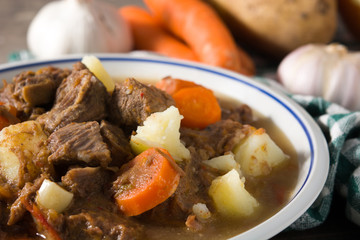 Irish beef stew with carrots and potatoes on wooden table.Close up
