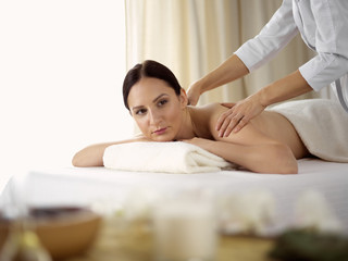 Obraz na płótnie Canvas Pretty brunette woman enjoying procedure of back massage in spa salon. Beauty concept