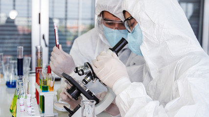 coronavirus covid-19 infected blood sample in sample tube on hand of scientist in biohazard...